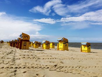 Hooded chairs at beach against sky