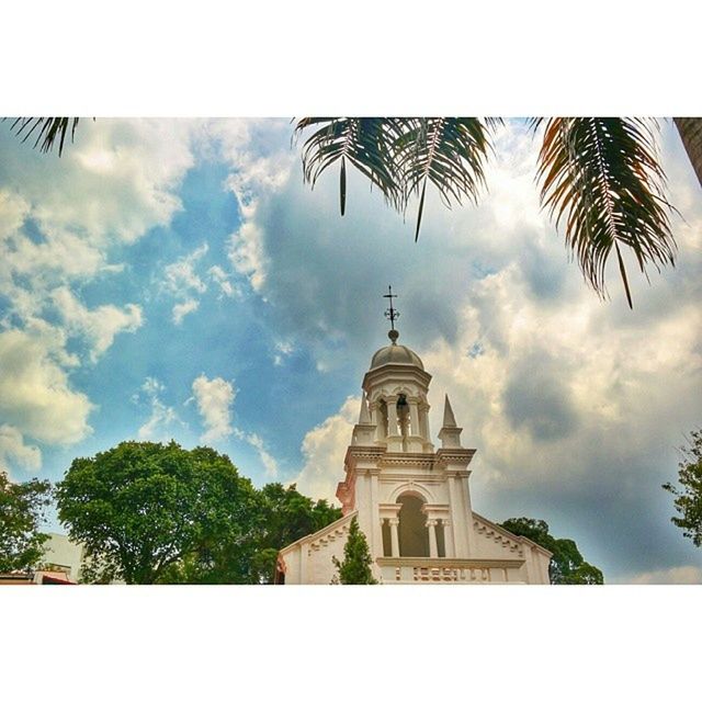 low angle view, sky, architecture, tree, building exterior, built structure, religion, palm tree, cloud - sky, place of worship, cloud, spirituality, church, cloudy, day, high section, auto post production filter, no people