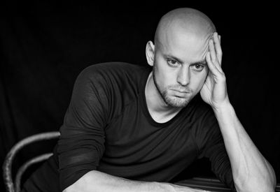 Portrait of young man sitting against black background