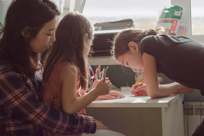 Mother and daughters draw together at home, authentic family life and candid lifestyle in apartment