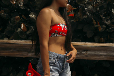 Midsection of woman standing against plants