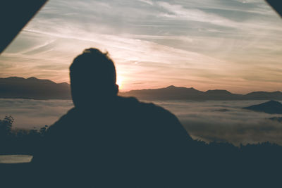 Silhouette man looking at sunset