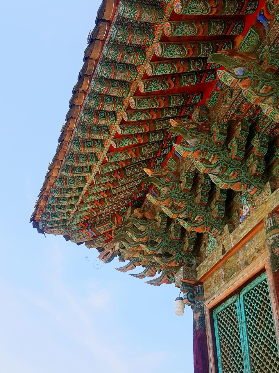 low angle view, architecture, built structure, building exterior, clear sky, red, religion, tradition, place of worship, cultures, spirituality, temple - building, roof, hanging, outdoors, sky, no people, day, culture