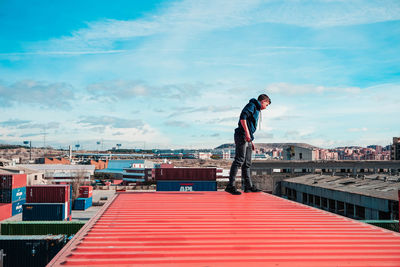 Man on a container looking down with a blue sky street urban photo