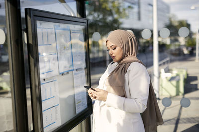 Woman using cell phone at bus stop