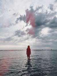 Rear view of man standing in sea against sky