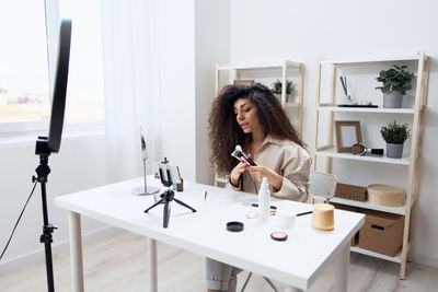 Woman making tutorial while applying makeup