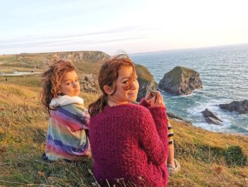 Rear view of women on sea shore against sky