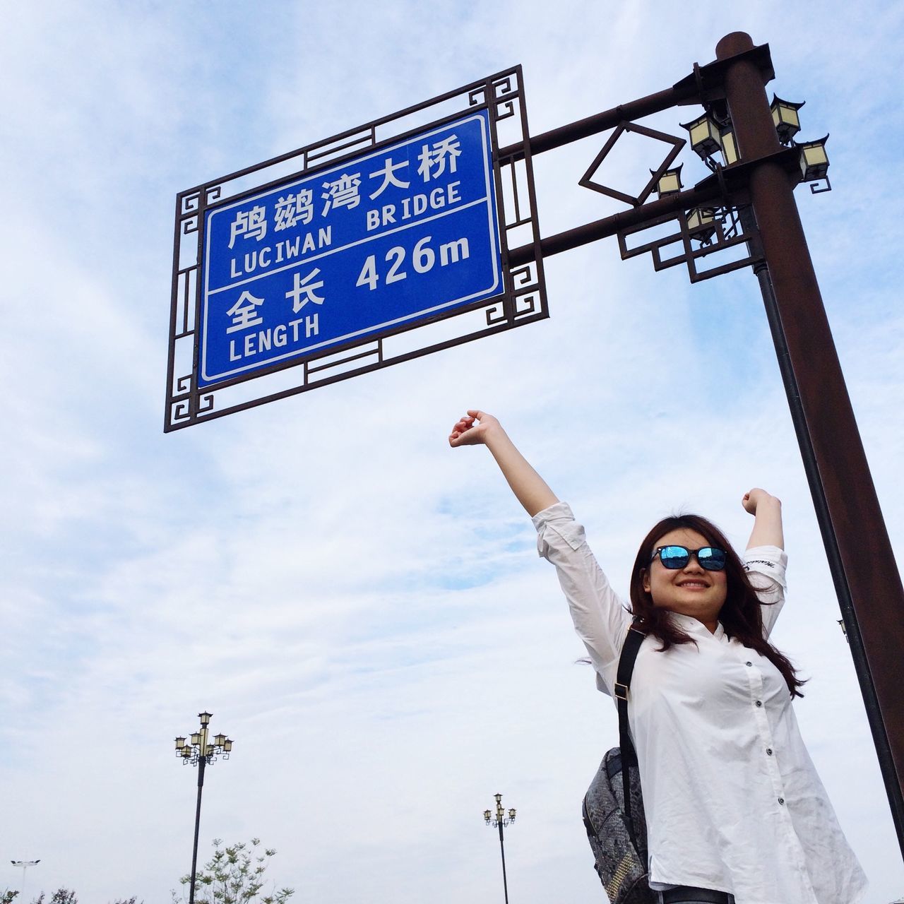 low angle view, communication, text, sky, western script, lifestyles, leisure activity, person, casual clothing, young men, road sign, standing, guidance, sign, front view, day, cloud - sky, information sign