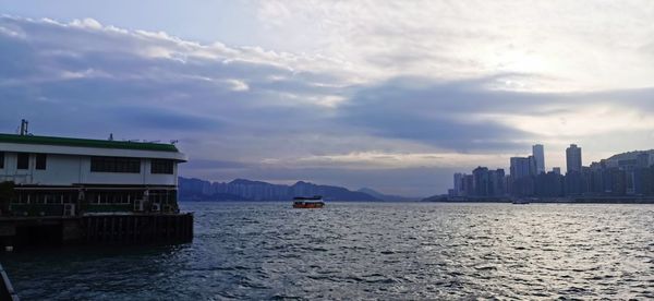 Scenic view of sea by city buildings against sky