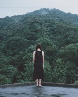 Rear view of woman standing by tree against mountain