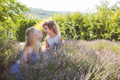 Mother kissing daughter amidst flowering plants