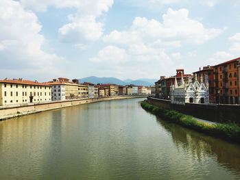 Bridge over river by buildings against sky in city