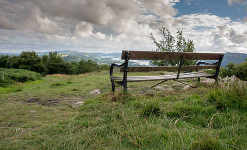 Empty chair on field against sky