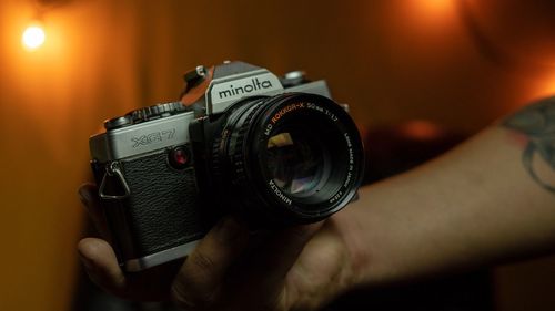 Close-up of hand holding camera in darkroom