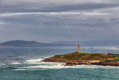 Lighthouse by sea against sky