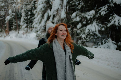 Portrait of smiling young woman standing in snow