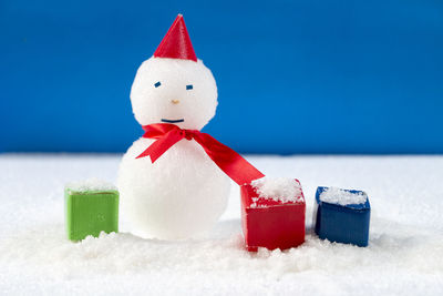 Close-up of christmas decorations on snow against blue background