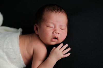 Close-up of baby boy against black background