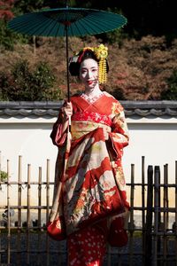 Portrait of smiling young woman standing against built structure