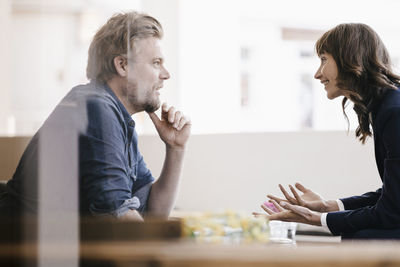 Man and woman sitting in cafe, discussing vividly