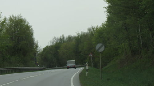 Cars on road amidst trees against sky