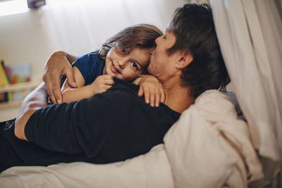 Portrait of smiling girl with mature father lying on bed