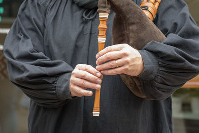 Midsection of man playing bagpipe while standing outdoors