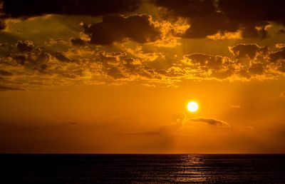 Scenic view of sea against dramatic sky during sunset