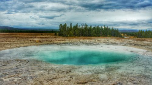 Scenic view of geyser basin against sky