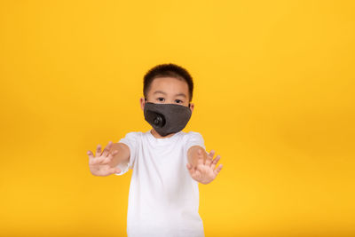 Portrait of boy standing against yellow background