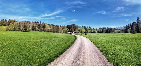 Road amidst field against sky