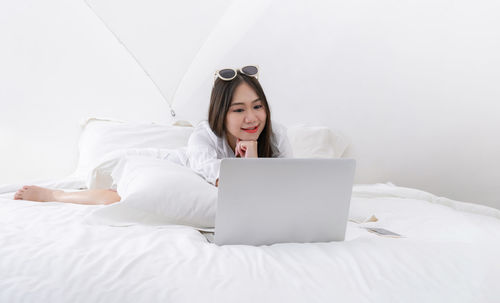 Young woman using mobile phone on bed