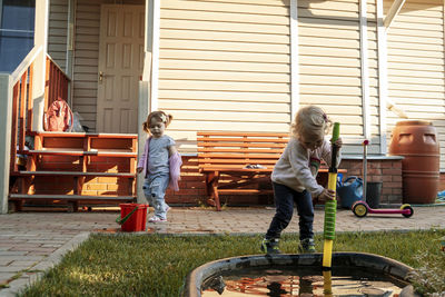 Children playing in the garden with water pump near a small pond.