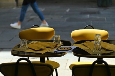 Empty chairs and tables at sidewalk cafe in city