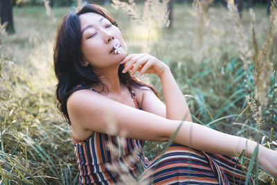 Side view of young woman sitting on field
