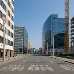 Road by modern buildings against sky in city