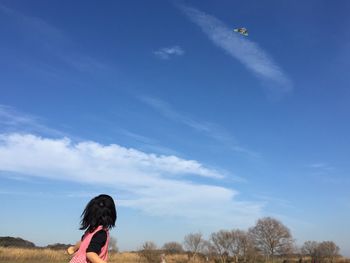 Rear view of girl standing against cloudy sky