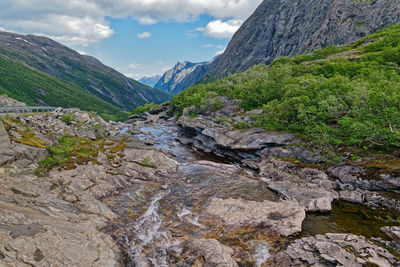 Scenic view of stream amidst rocks against sky