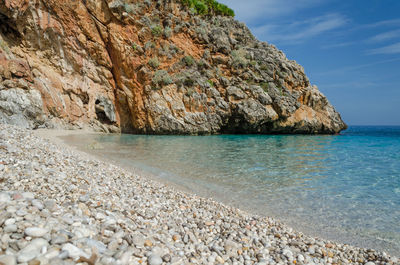 Rock formation on beach against sky