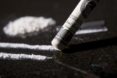 Close up of cocaine with rolled up american currency on table