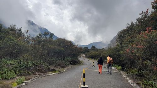 Rear view of man walking on road against mountain