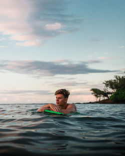 Thoughtful man swimming in sea against sky