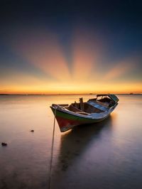 Boat in sea against sky during sunset