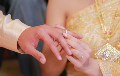 Midsection of wedding couple exchanging finger rings during ceremony