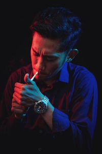 Man lighting cigarette against black background