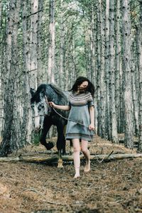 Full length of woman with horse walking in forest
