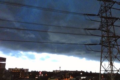Low angle view of electricity pylon against cloudy sky