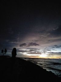 Silhouette beach against sky during sunset