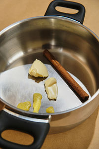 Steel pot prepared with cinnamon, lemon and butter for pouring milk an